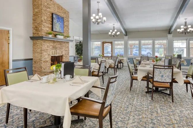 A dining room with a stone fireplace and a wall of windows.